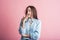 Exhausted brunette girl yawns in studio on pink background.