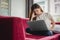 Exhausted businesswoman having a headache while using laptop on red sofa, Business worry and Stress concept, Online shopping and