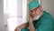 Exhausted elderly doctor sat down to rest on the floor in the hospital corridor.