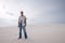 Exhausted man, lost in the desert, is standing on a sand dune