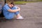 Exhausted Nurse sitting on the road leaning agianst her car