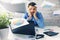 Exhausted office worker sitting by the desk with flying papers around