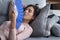 Exhausted overheated woman waving paper fan, lying on couch