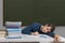 Exhausted and overworked teacher is sleeping on desk in classroom