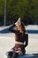 Exhausted skater female sitting in a concrete pool with a glass bottle of cold water in hand. Cool young adult roller blader