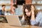 Exhausted stressed young woman with tousled hair using laptop