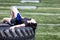 Exhausted teen girl resting on heavy truck tire in middle of sports field during hot day