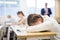 Exhausted teen girl sleeping at desk during lesson