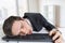 Exhausted or tired businessman is sleeping on keyboard in office