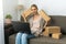 Exhausted tired woman small craft business owner sitting on couch with boxes and laptop. processes and prepares shipments from the