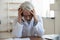 Exhausted unhappy mature doctor wearing glasses sitting at desk