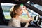 Exhausted woman driver feeling headache, sitting inside her car, applies a bottle of water to his forehead, hot weather