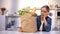 Exhausted woman looking at heavy paper bag with food, problems with delivery