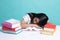 Exhausted Young Asian woman sleep with books on table