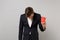 Exhausted young business man in classic black suit with lowered head holding paper cup with coffee or tea isolated on