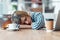 Exhausted young business woman who has fallen asleep while working wirh laptop in living room at home