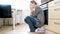 Exhausted young housewife crying on floor at kitchen