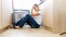 Exhausted young housewife leaning on washing machine at laundry