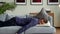 Exhausted young man falling asleep on couch, feeling no energy after hard working day. Businessman flopping down on sofa