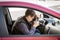 Exhausted young man sleeping on drivers seat while driving a car