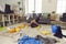 Exhausted young woman fallen on the floor while cleaning up her messy living-room