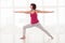 Exhilarated woman standing in warrior pose, practicing yoga or p