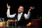 An exited bartender at a bar counter, oranges, lemon, a shaker, margarita glasses on a black background.