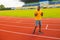 Exited joyful male athlete standing on racetrack. Sporty afro man jogging at stadium track. African american runner