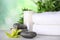 Exotic flower, spa stones, candle and towels on table against blurred green background, space for text