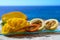 Exotic fruits, fresh ripe sweet yellow mango and passion fruits served on glass plate with blue seaview background