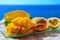 Exotic fruits, fresh ripe sweet yellow mango and passion fruits served on glass plate with blue seaview background