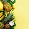 Exotic pineapples, coconuts, banana, melon, lemon, palm and monstera leaves on yellow, violet background with copyspace