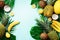 Exotic pineapples, ripe coconuts, banana, melon, lemon, tropical palm and green monstera leaves on blue background with