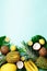 Exotic pineapples, ripe coconuts, banana, melon, lemon, tropical palm and green monstera leaves on blue background with