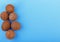 Exotic tropical nuts on the left side. Natural, organic whole coconuts on a blue background. Six fresh cocos, top view.