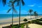 Exotic tropical vibrant coastal waterscape gardens with palm trees in a blue sky over ocean water. Thailand