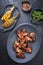 Exotically barbecue chicken wings with hot chili sauce, jalapeno and pineapple on a cast iron plate