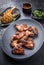 Exotically barbecue chicken wings with hot chili sauce, jalapeno and pineapple on a cast iron plate