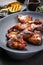 Exotically barbecue chicken wings with hot chili sauce, jalapeno and pineapple on a cast iron plate