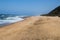 Expansive Beach Sand with Deep Blue Ocean and Clear Sky