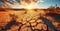 Expansive Desert Landscape with Cracked Earth Foreground Leading to Rolling Sand Dunes Under a Golden Sunrise, Symbolizing Aridity