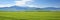 Expansive green fields under a serene blue sky with fluffy white clouds, a breathtaking sight