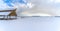 Expansive landscape blanketed with snow under a cloudy blue sky in winter under