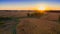 Expansive outdoor landscape featuring a bright orange sunset over the corn field