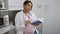 Expectant young woman scientist, immersed in a profound chemistry book read at her lab workstation, fusing motherhood and medical