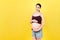 Expecting mother in unzipped jeans showing her naked pregnant belly at colorful background with copy space. Pregnancy concept