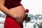 Expecting pregnant woman holding her beautiful belly and red rose flower