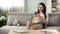 Expecting woman on couch typing message on mobile phone, pregnancy app on gadget