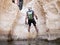 Experienced athlete descending with equipment for rappel in mountains of Judean Desert, into the water of the Rahaf stream, near