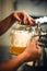 Experienced bartender pouring draft beer into a glass.